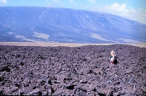 A’a lava field on Fernandina, Galápagos, on the northwest coastline. Walking across a flow like this can be an extremely painful experience. Note the ‘tortoise-shell’ profile of the volcano’s summit in the background