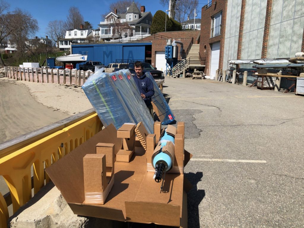Aiden Thayer prepares Argo floats on the waterfront at Maine Maritime Academy. Each float is tested and initialized prior to loading on the vessel. One float is shown unboxed so that students could see the instrument and sign their names on the hull.